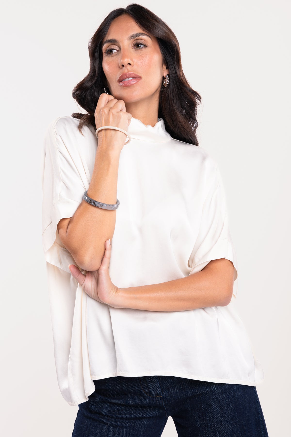 Une blouse à col montant écrue et un pantalon en jean brut 