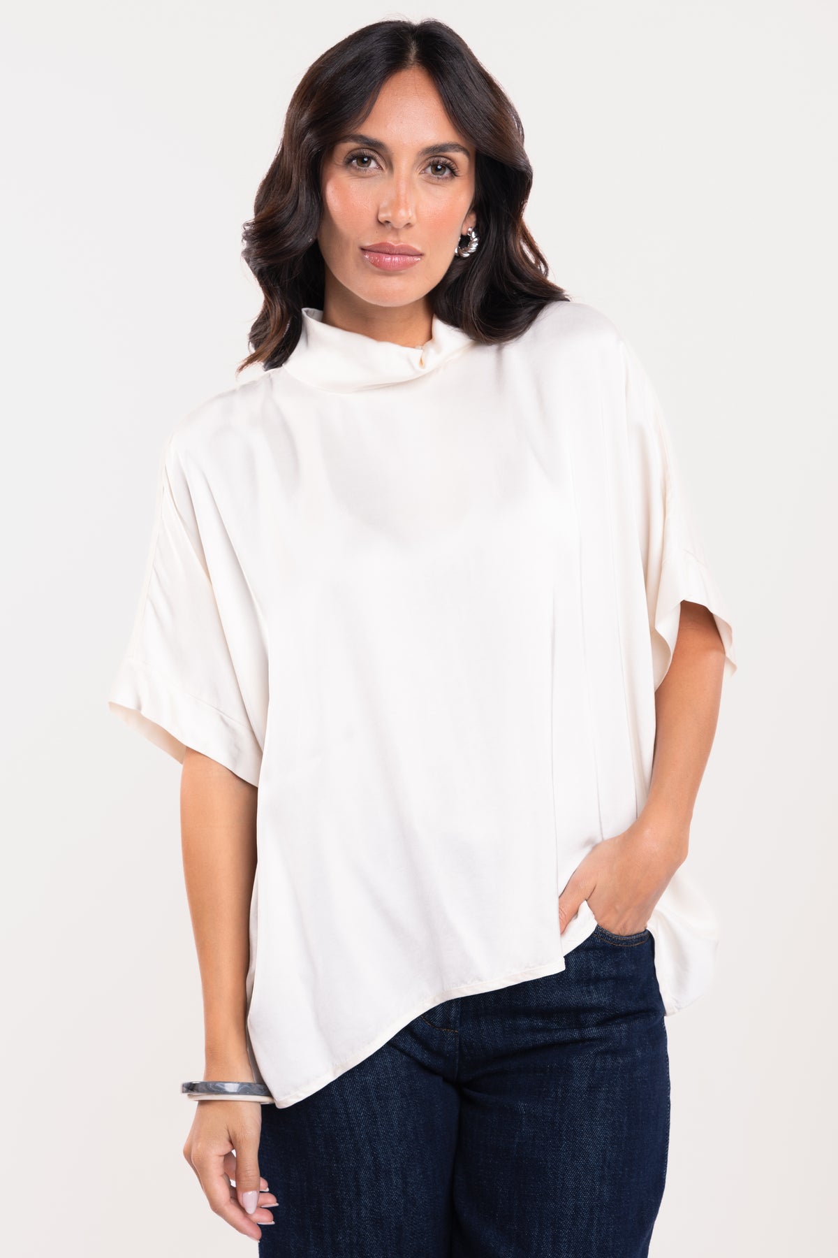 Une blouse à col montant écrue et un pantalon en jean brut 