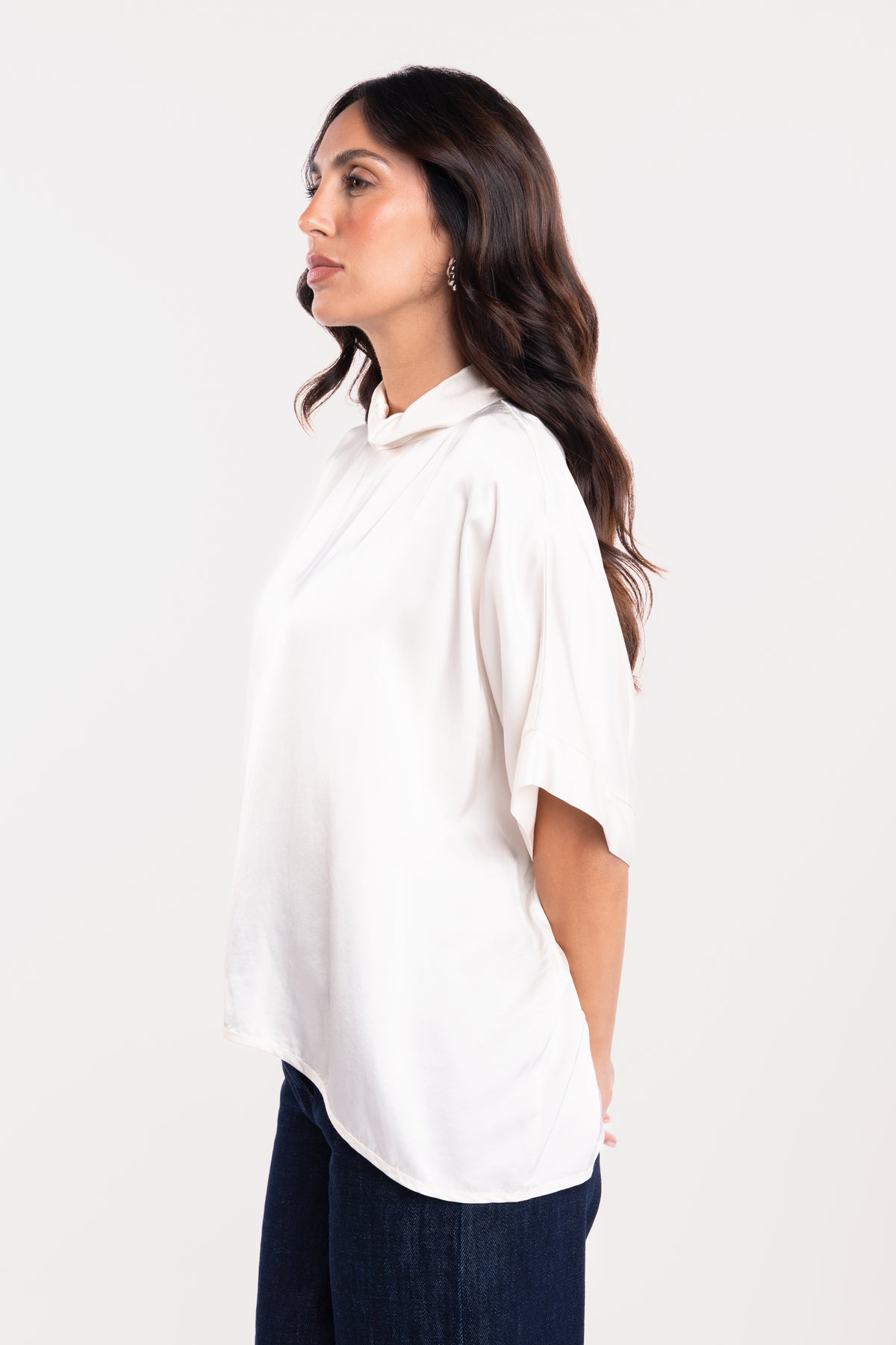 Une blouse à col montant écrue et un pantalon en jean brut 