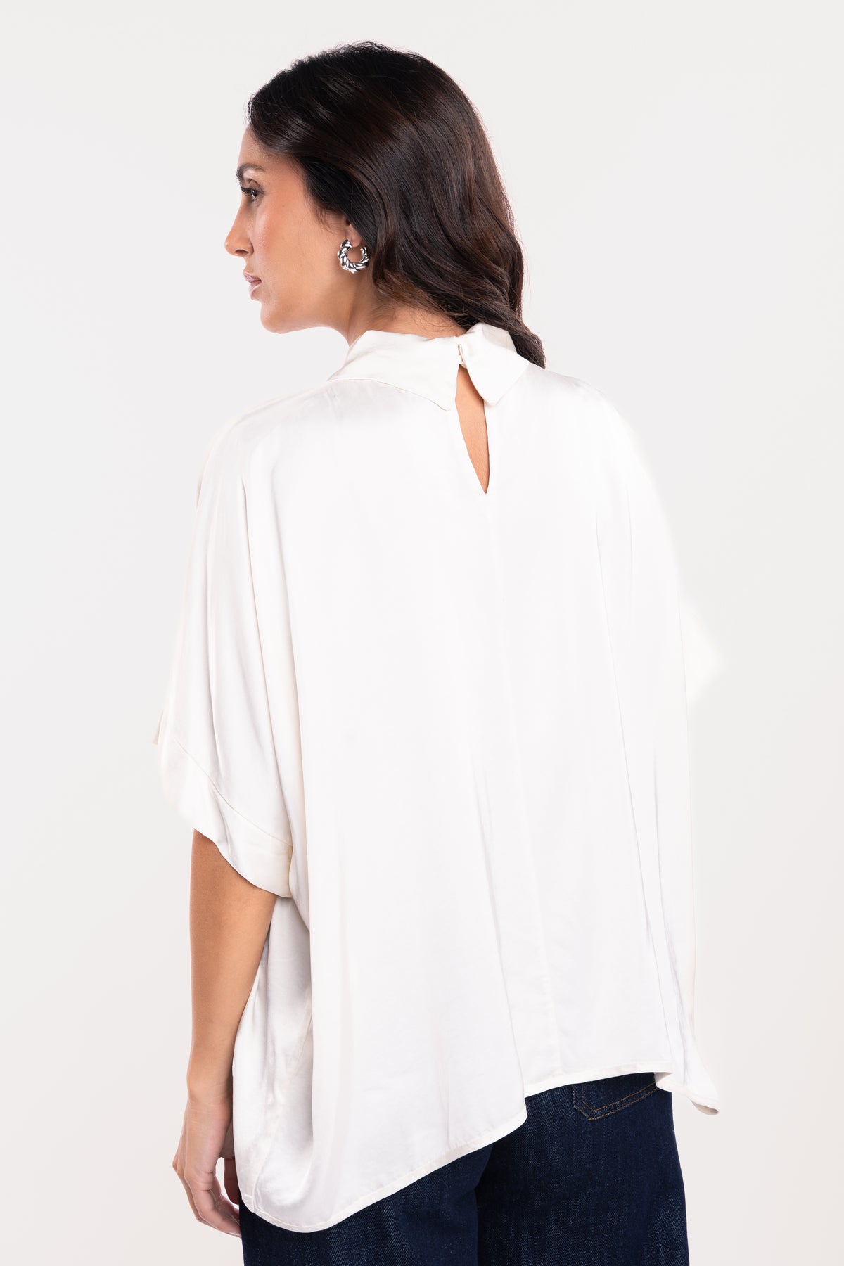 Une blouse à col montant écrue, un pantalon en jean brut