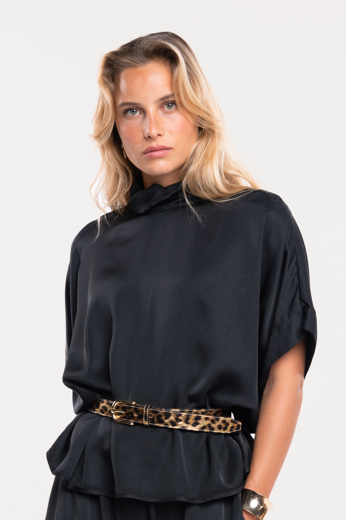 Une blouse noire à col montant, une ceinture imprimée léopard