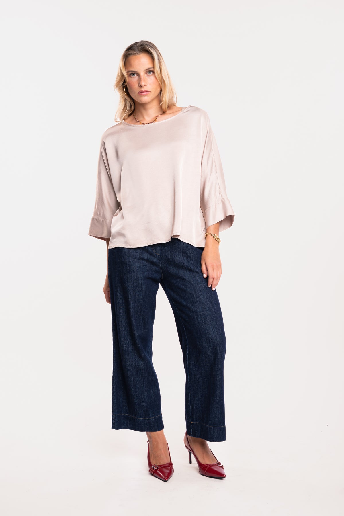 Une blouse en satin beige, un jean brut 7/8ᵉ et une paire de talons rouges 