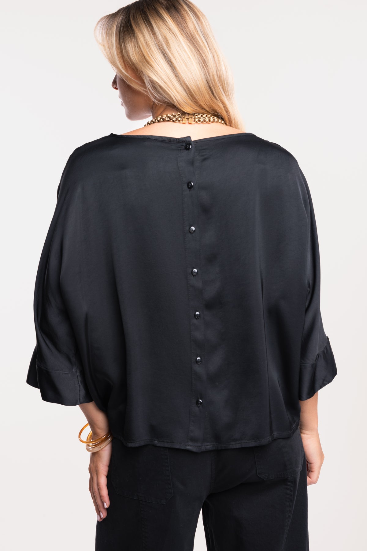 Une blouse en satin noire et un pantalon barrel noir de dos