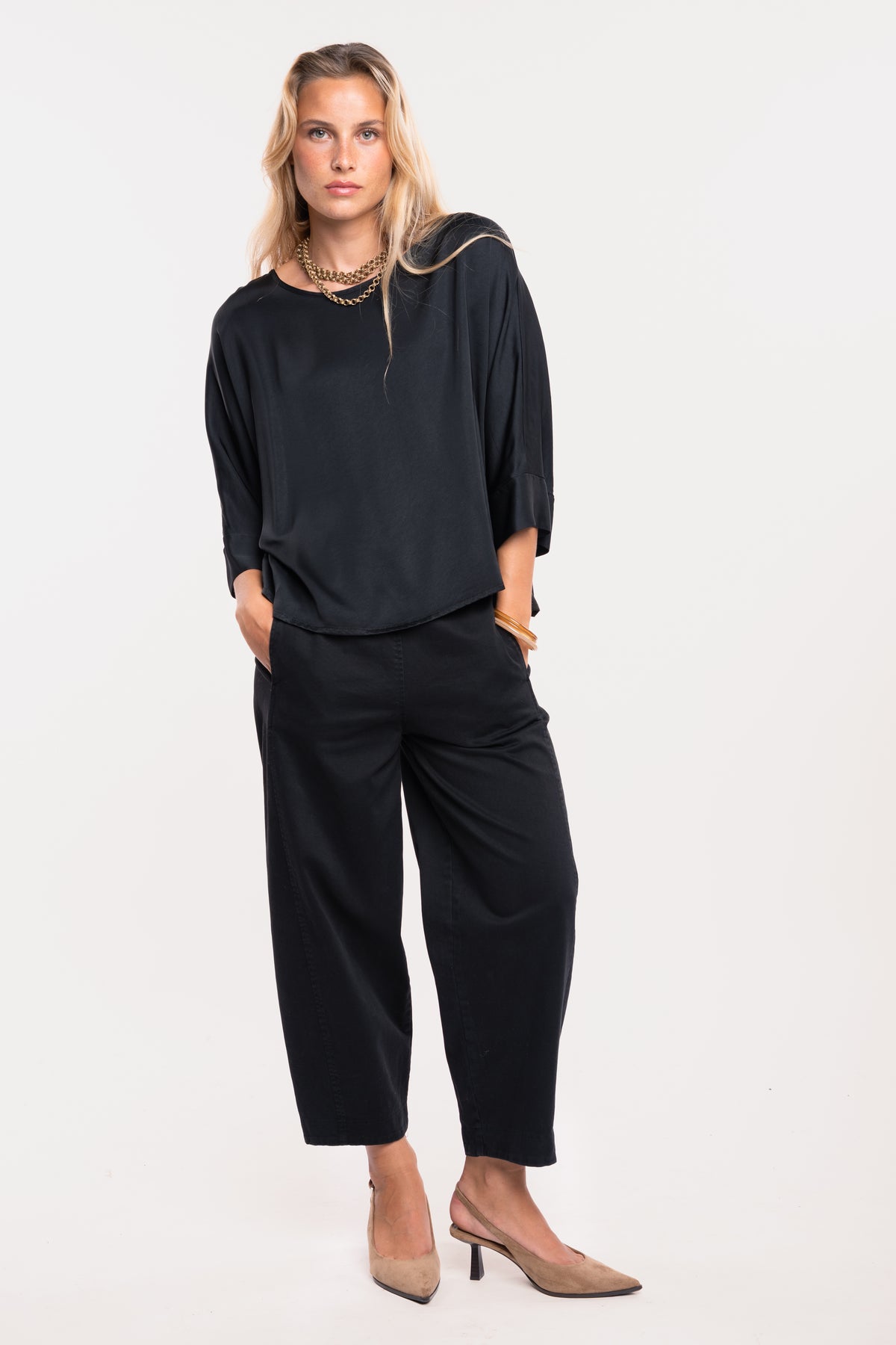 Une blouse en satin noire, un pantalon barrel noir et une paire de talons beiges