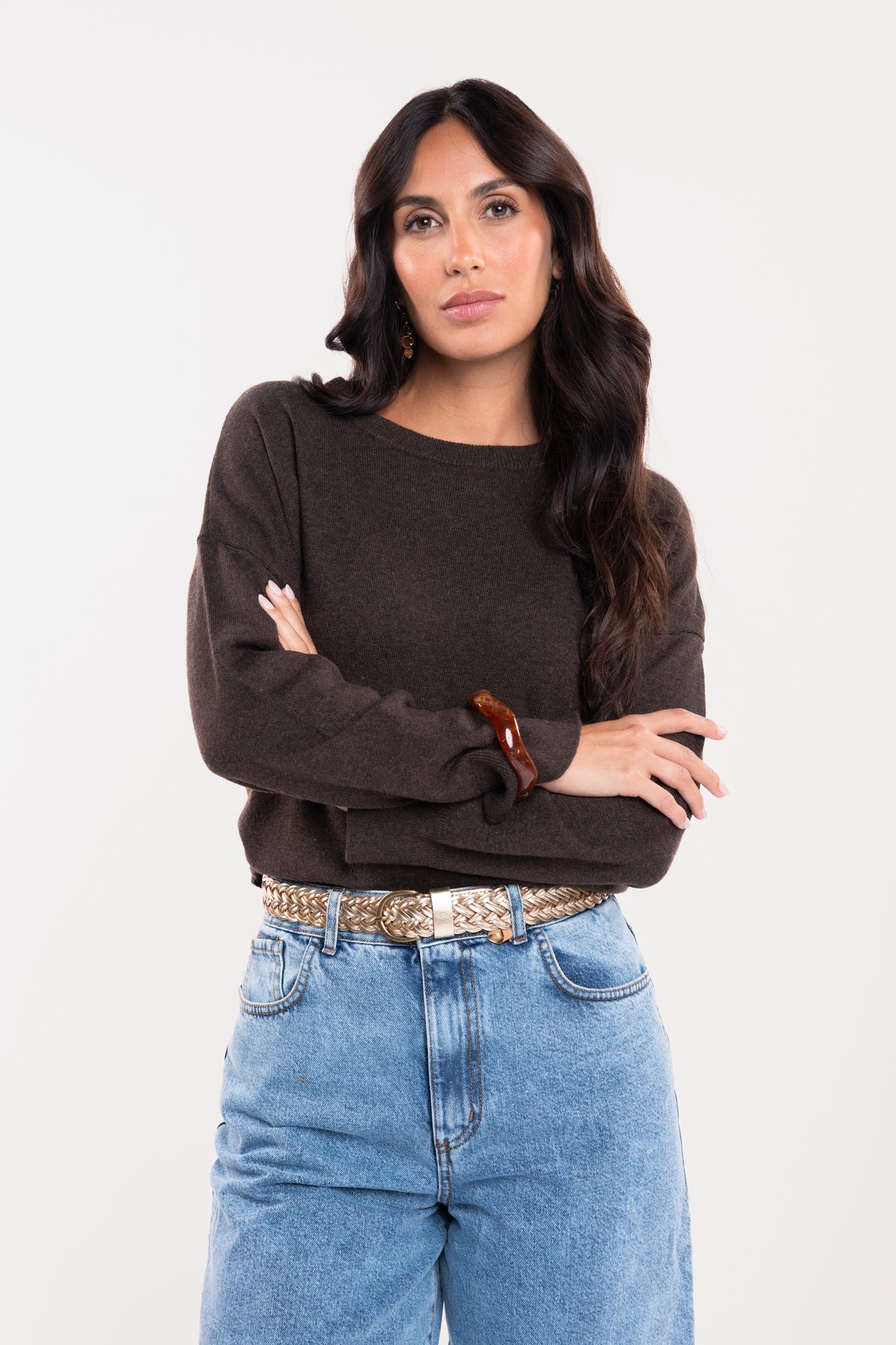 Pull oversize marron avec une ceinture tressée doré et un jean évasé délavé clair 