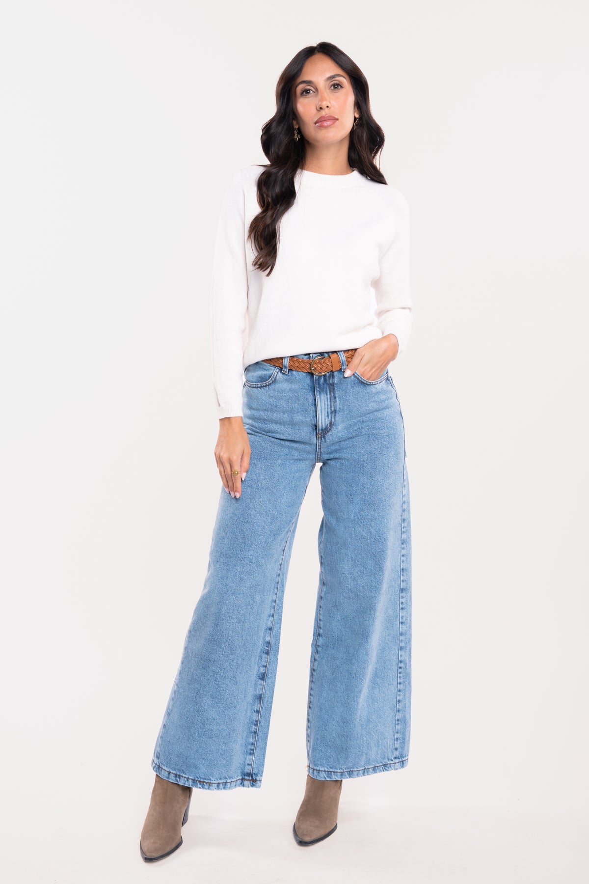 Pull ample écru avec une ceinture tressée couleur tabac, jean évasé délavé et paire de bottes beiges