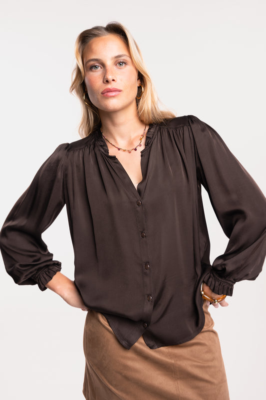 Une chemise en satin marron et une jupe courte en suédine camel