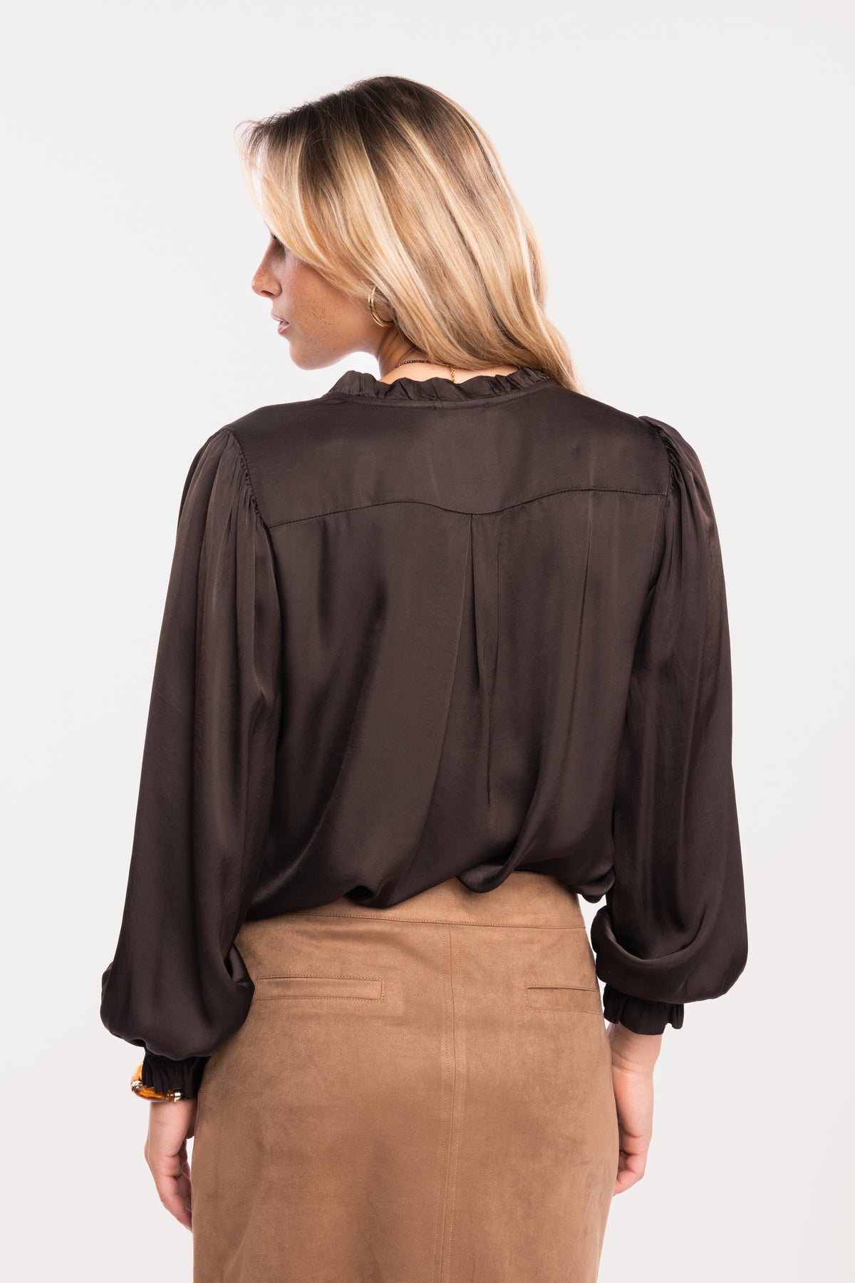 Une chemise en satin marron et une jupe courte en suédine camel de dos
