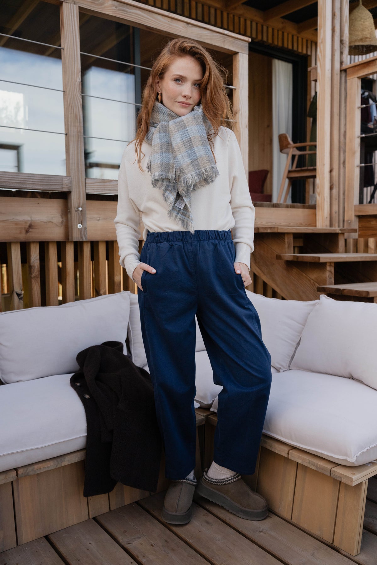 Caban court marron avec une écharpe à carreaux bleu ciel, pull écru et un pantalon barrel marine avec une paire de chaussure 