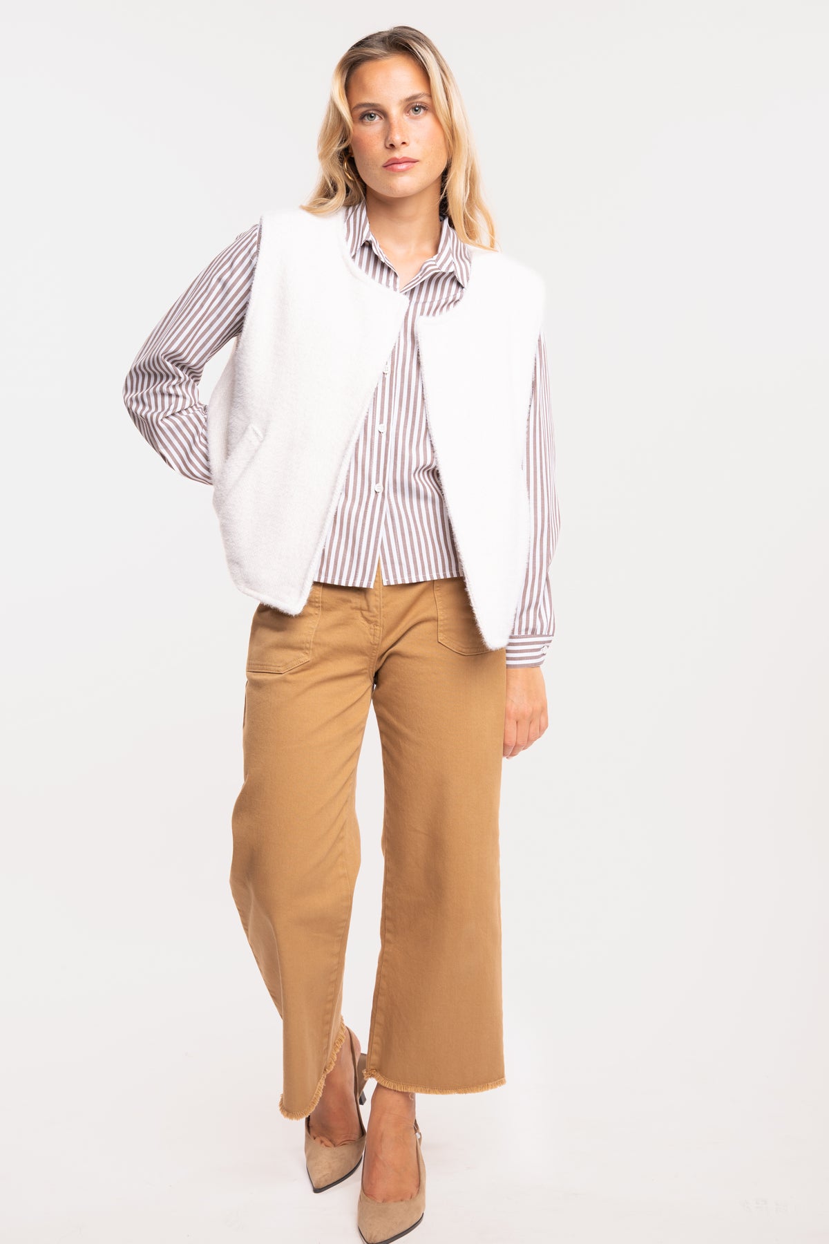 Gilet sans manches écru avec chemise à rayures marron et pantalon 7/8ème camel avec une paire de talons beiges