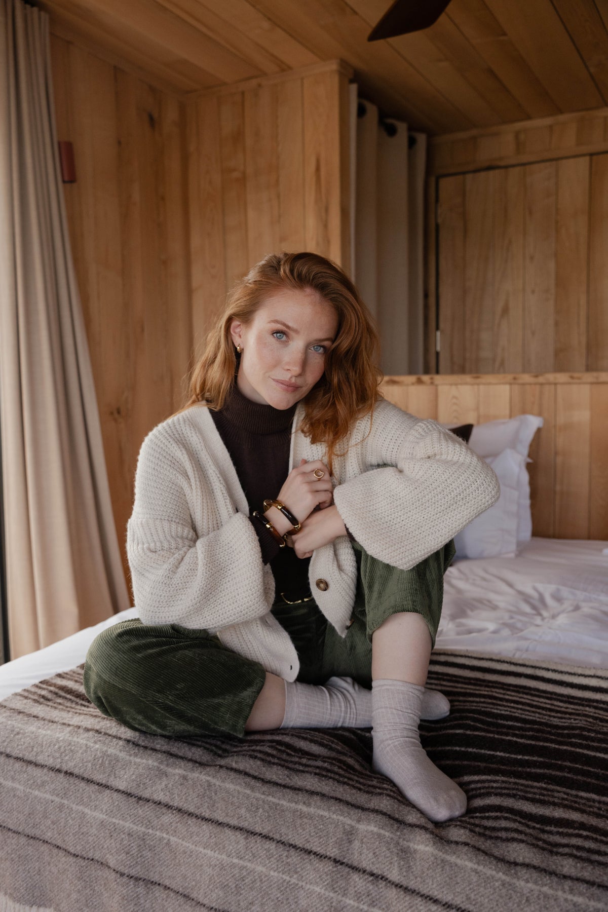 Gilet boutonné écru en maille avec un pull col roulé marron, une ceinture marron, un pantalon barrel kaki