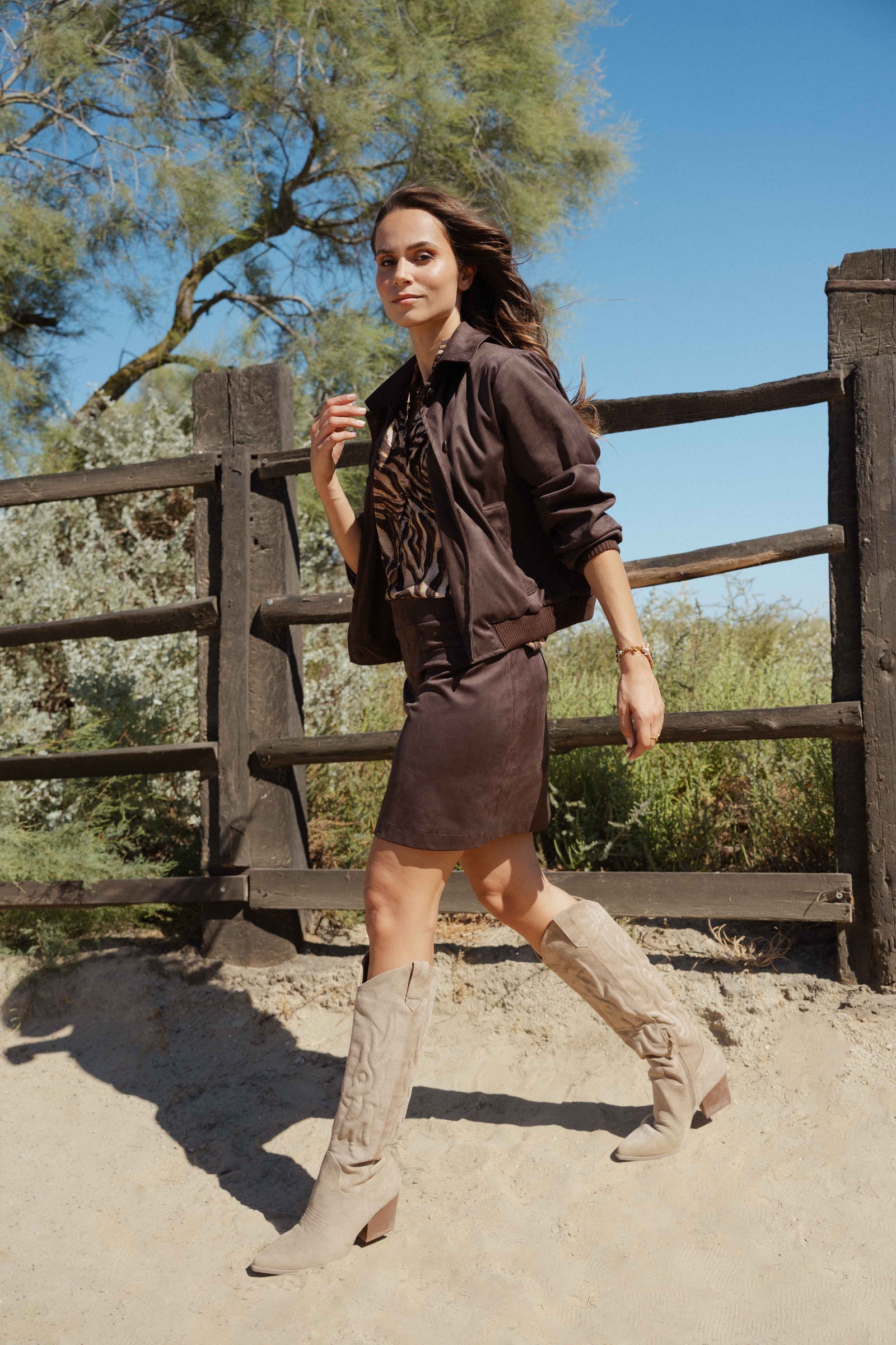 Veste suédine marron avec blouse zèbre imprimée marron, jupe courte suédine marron et santiags beige 