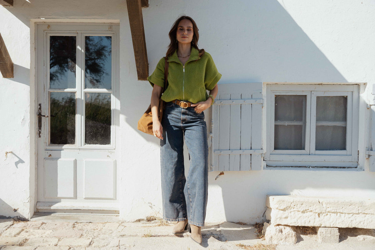 Veste zipée oversize vert olive, ceinture en daim marron, jean évasé délavé, sac cabas en cuir camel et bottes beiges à talon  