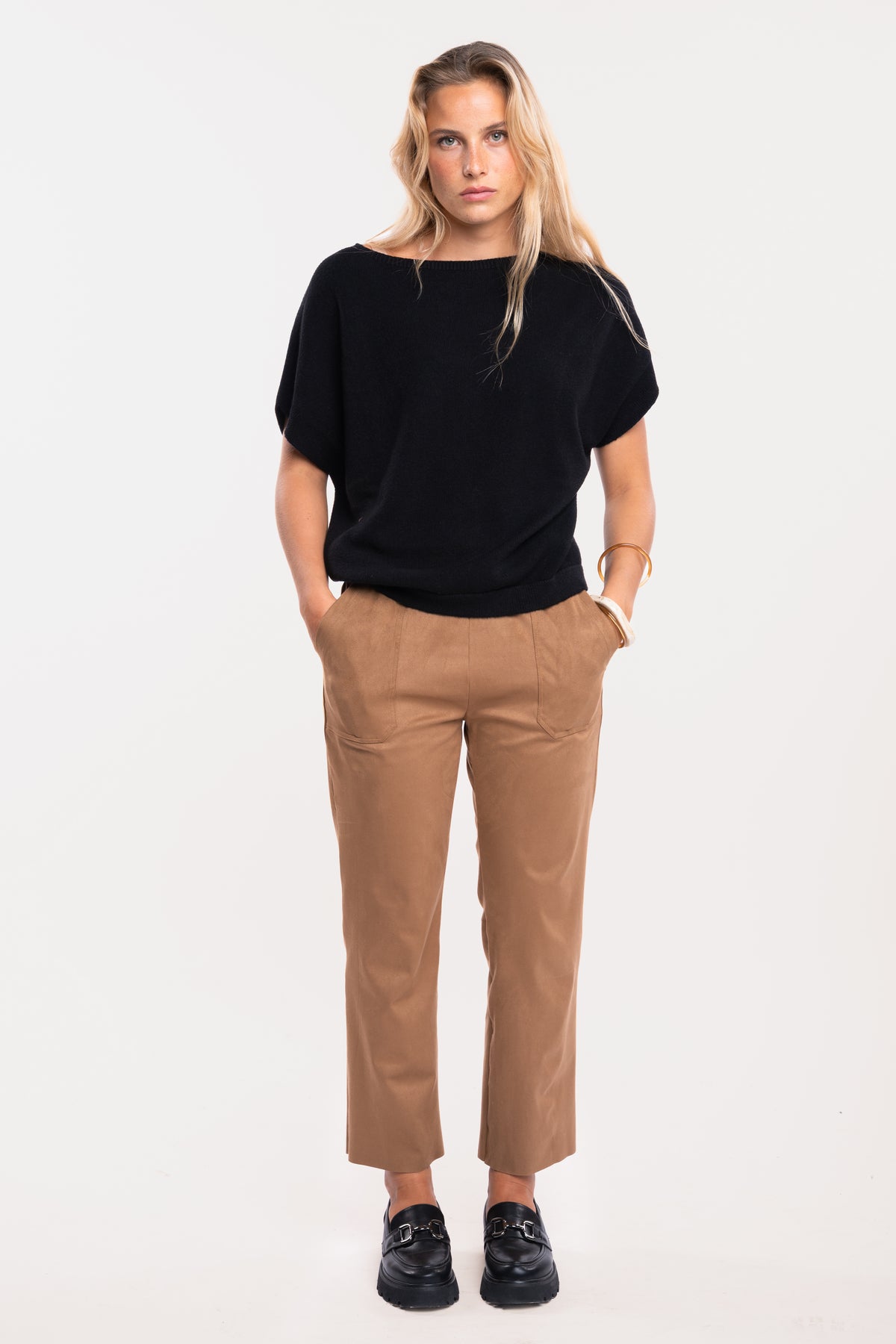 Pull sans manches noir avec un pantalon cintré camel et des mocassins noirs 