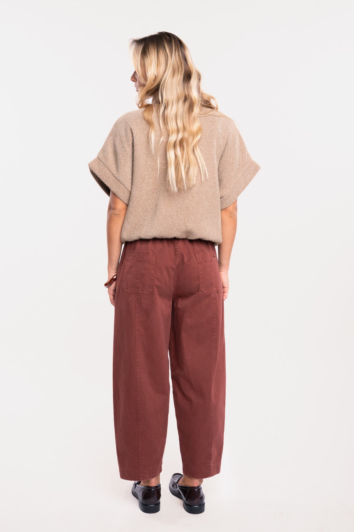 Veste zippée oversize camel avec un pantalon barrel acajou et paire de mocassins de dos  