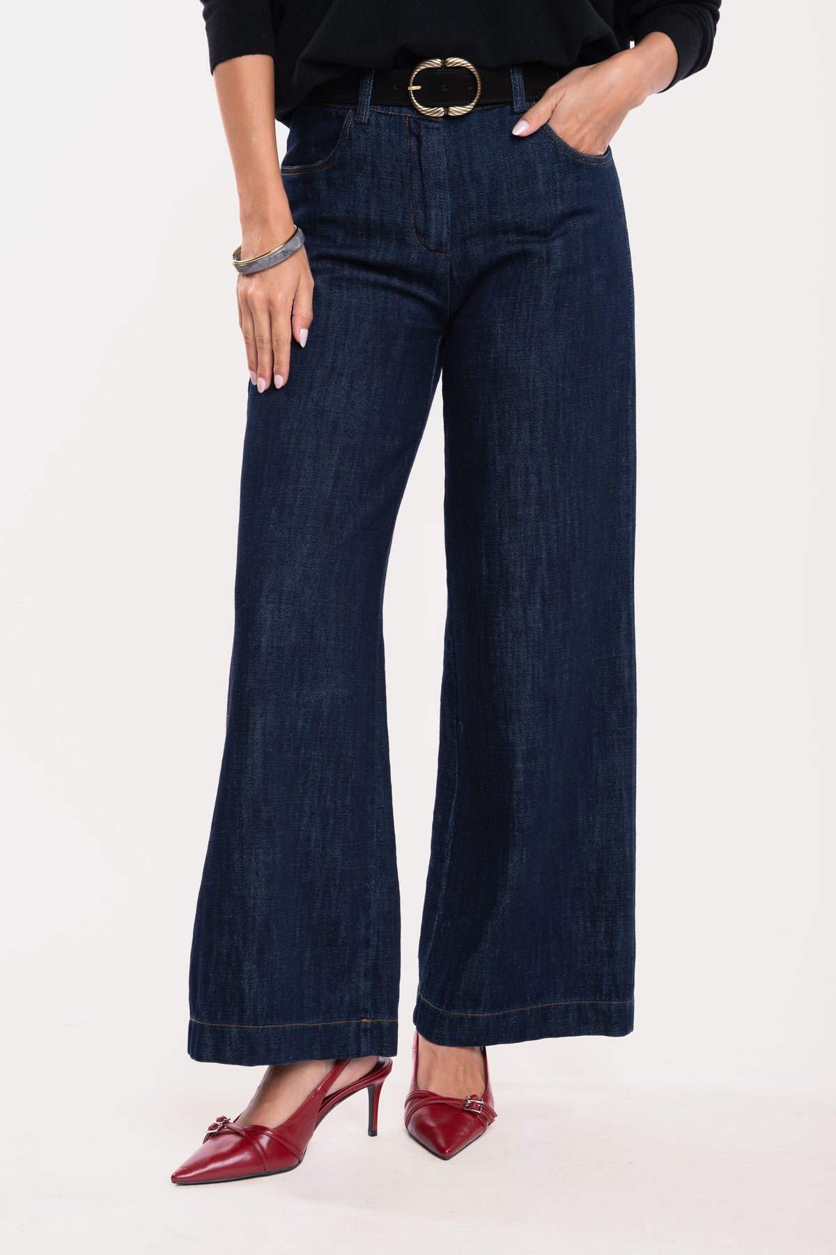 Ceinture en daim noir avec un pantalon en jean brut et une paire de talons rouges 