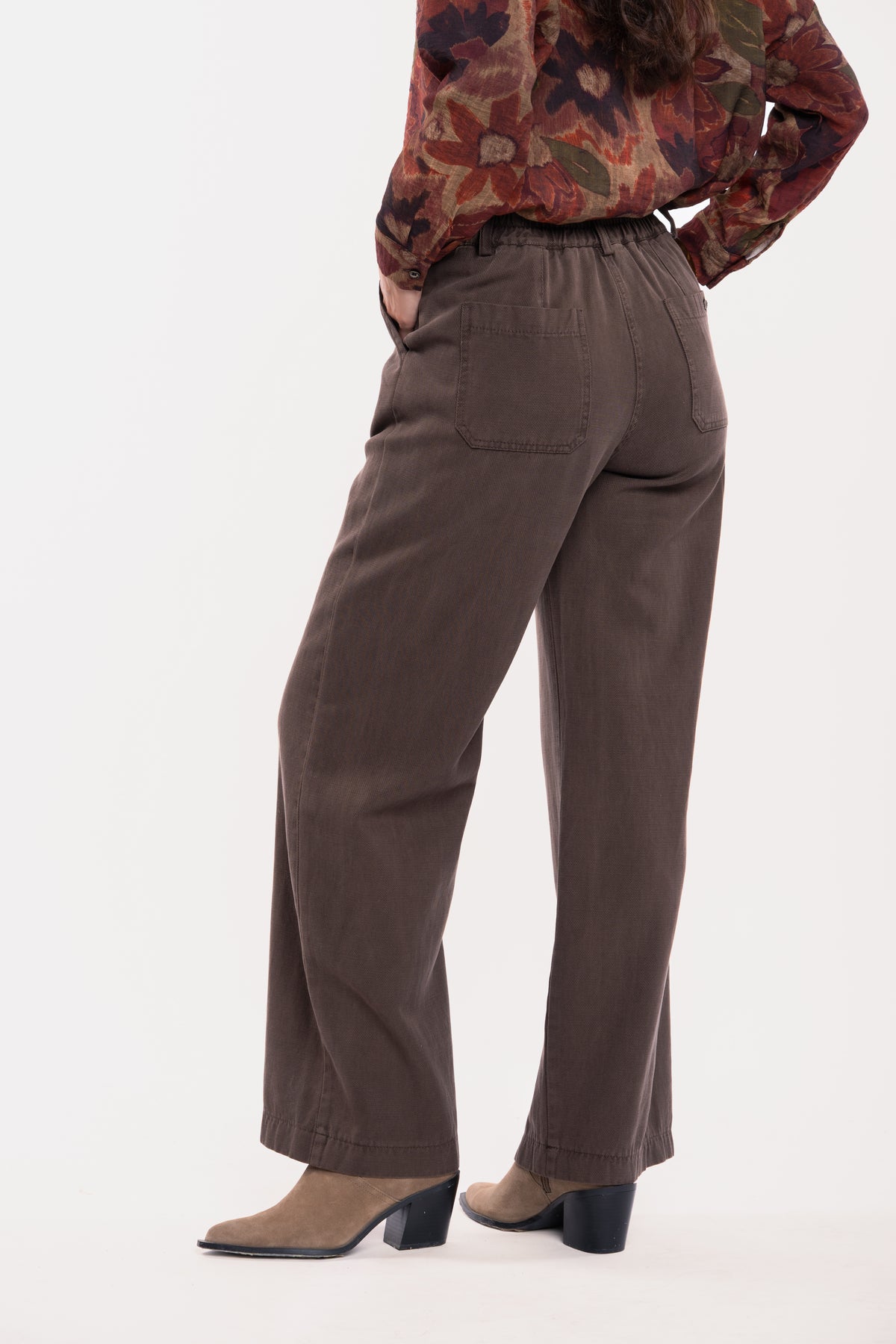 Chemise imprimée fleuris prune et pantalon évasé marron avec une paire de talons beiges de dos