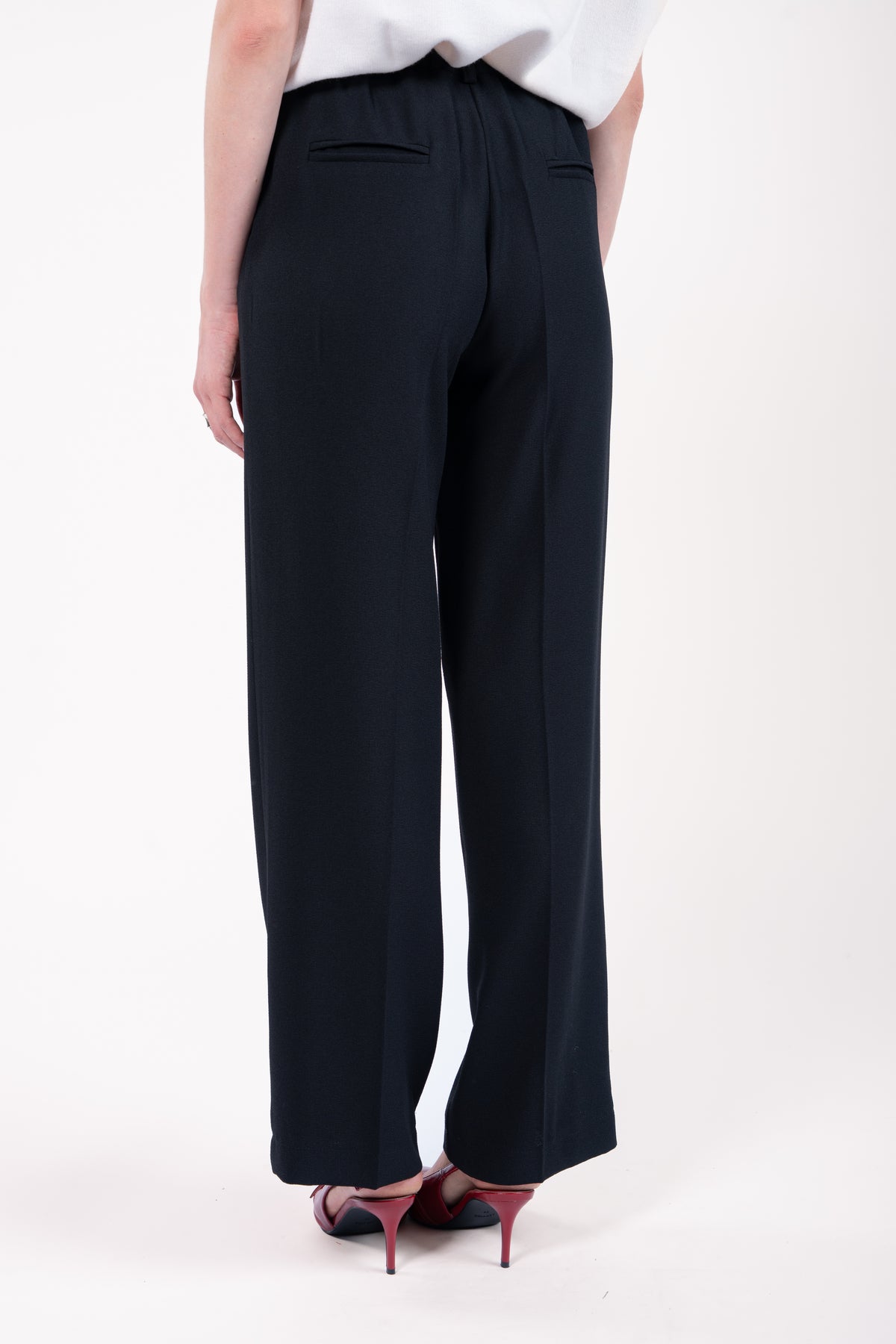 Pantalon évasé long noir et escarpin rouge de dos