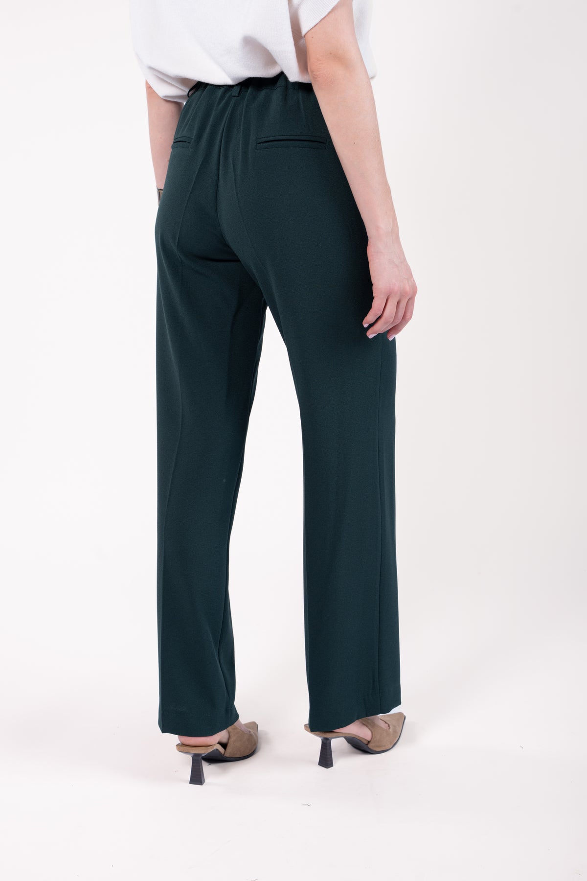 Pull col rond ample sans manches naturel avec pantalon évasé long vert et talon beige de dos