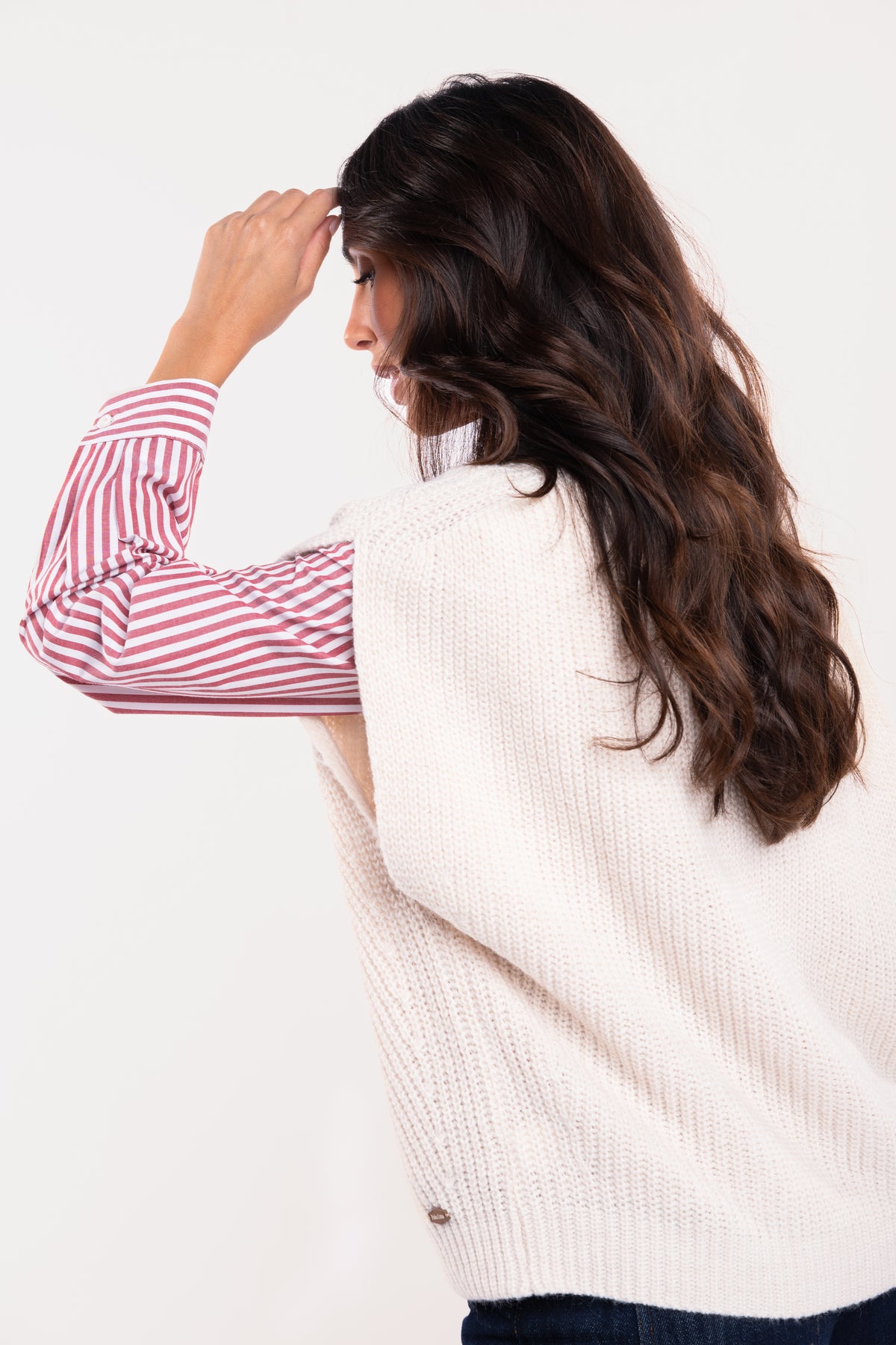 Un pull ample à col V écru, une chemise à rayures rouges de dos