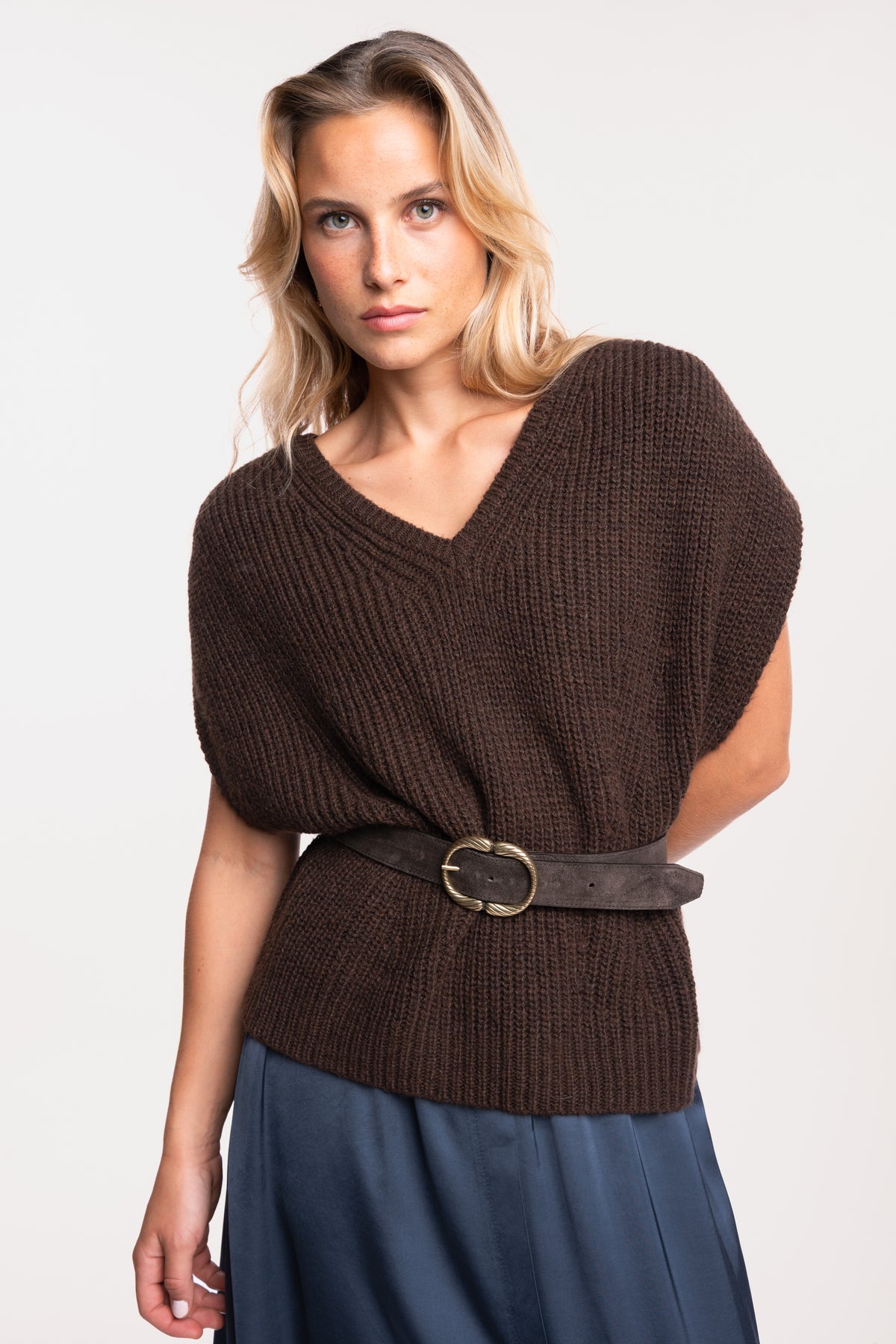 Un pull ample à col V marron, une ceinture en daim marron 