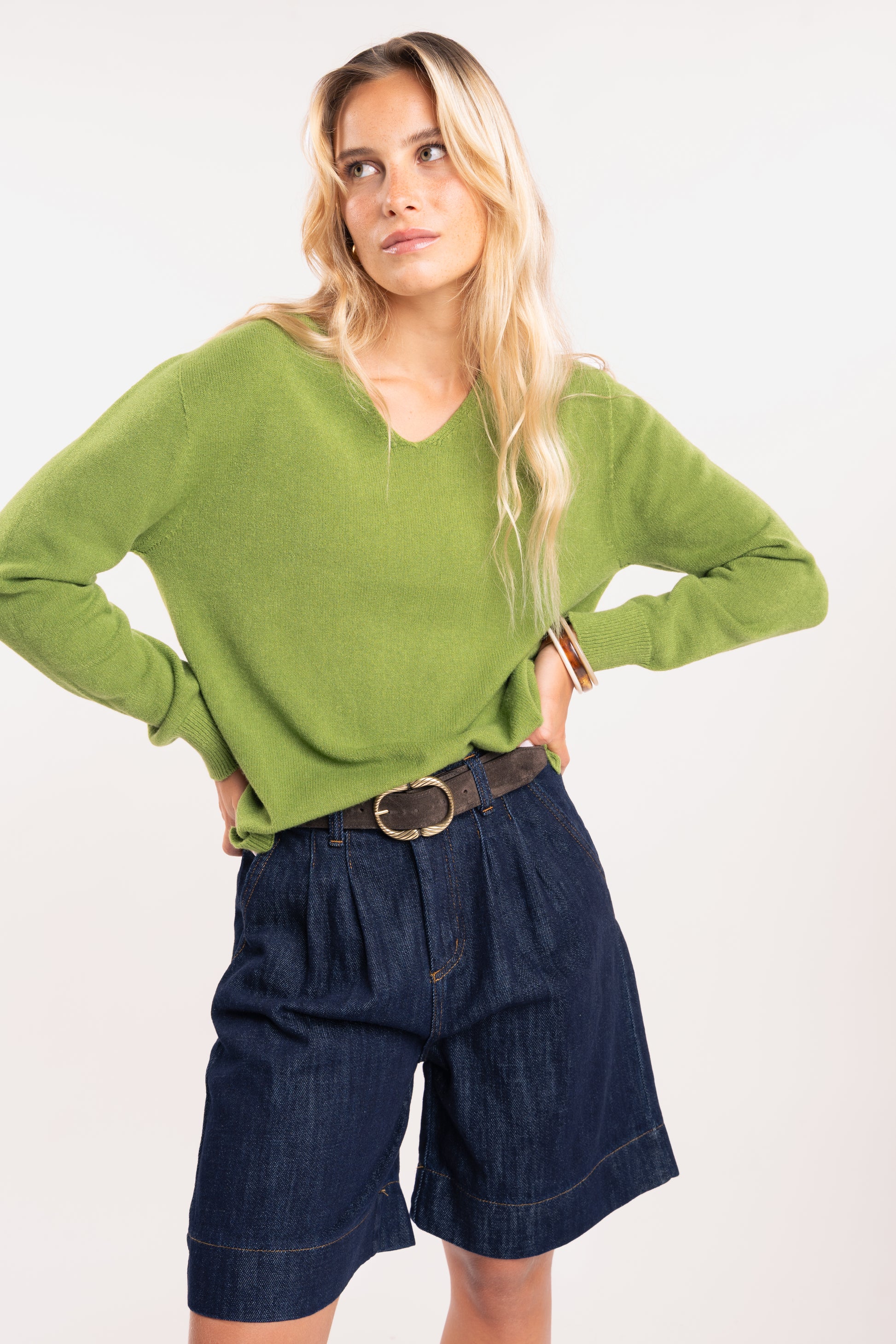 Pull ample femme vert, ceinture daim marron et bermuda long denim 