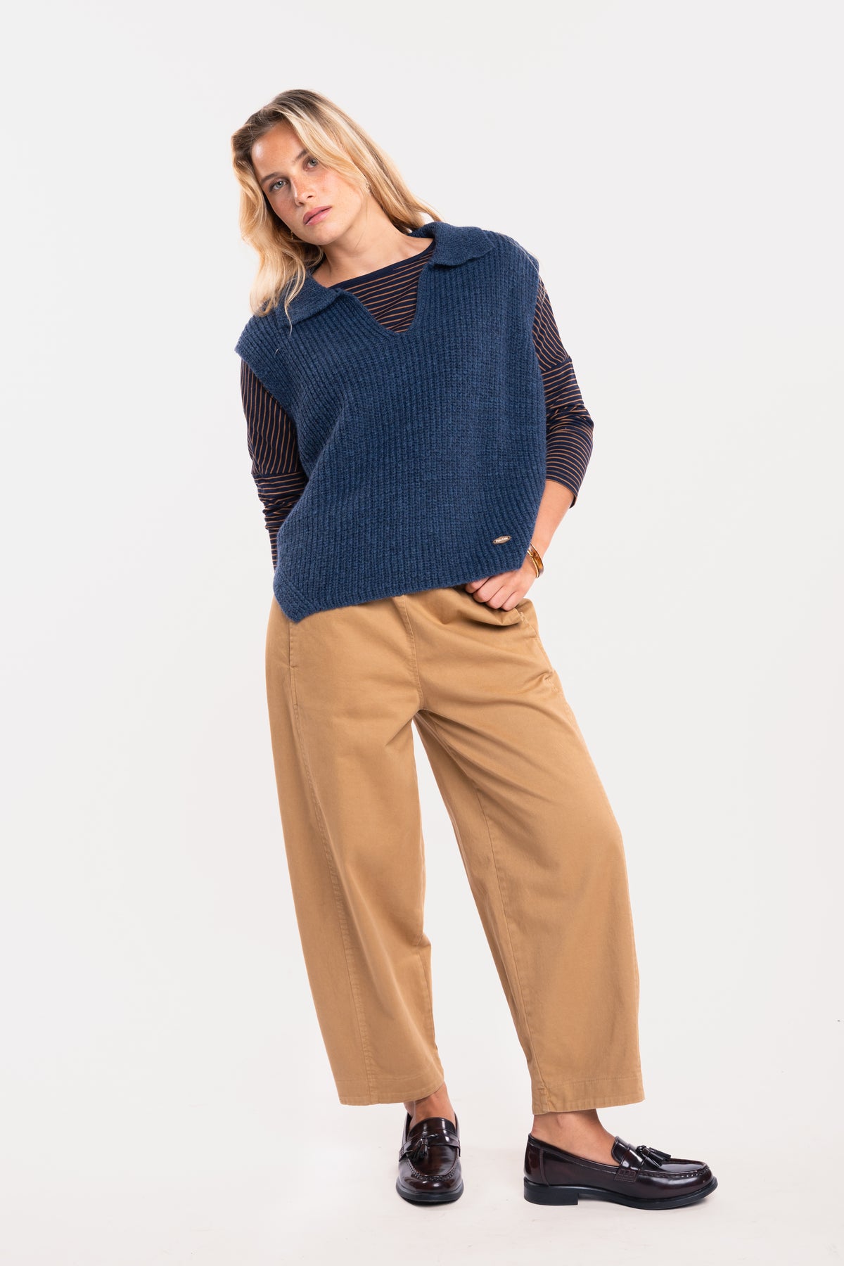 Un pull col polo bleu, un top à col bateau rayé marine et tabac, un pantalon barrel camel et une paire de mocassins