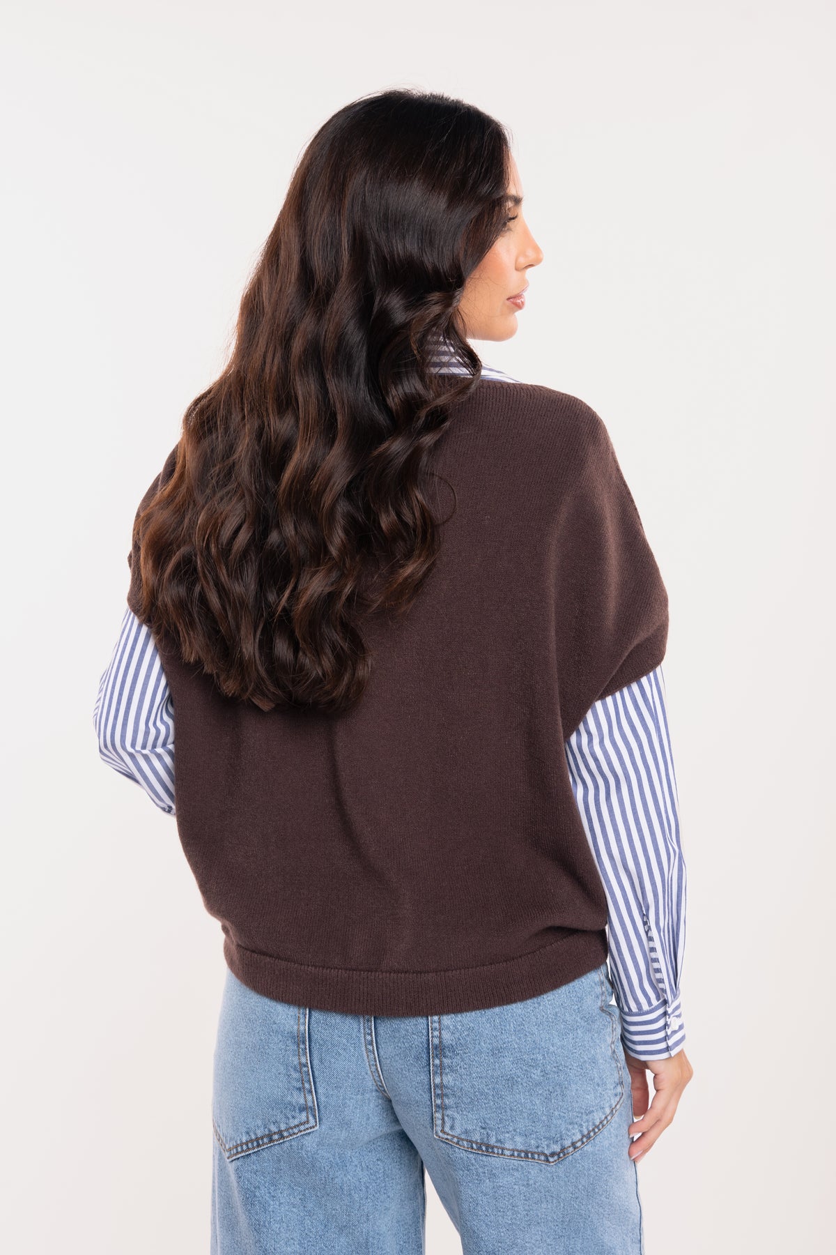 Pull sans manches marron avec chemise rayée bleu marine, jean évasé délavé clair de dos