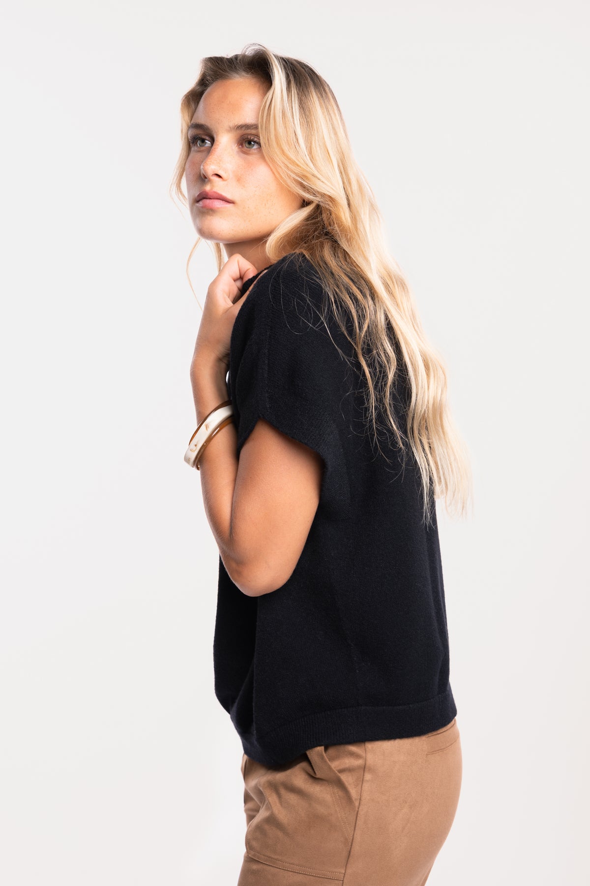 Pull sans manches noir avec un pantalon suédine cintré camel 