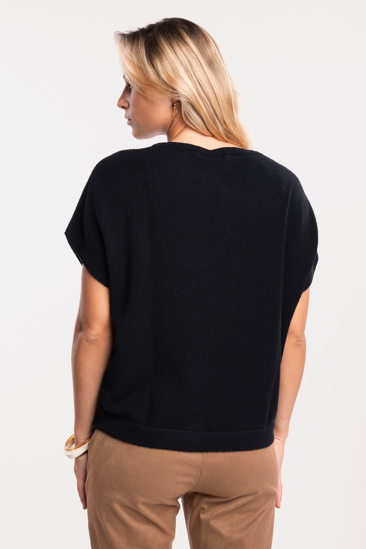 Pull sans manches noir avec un pantalon suédine cintré camel de dos
