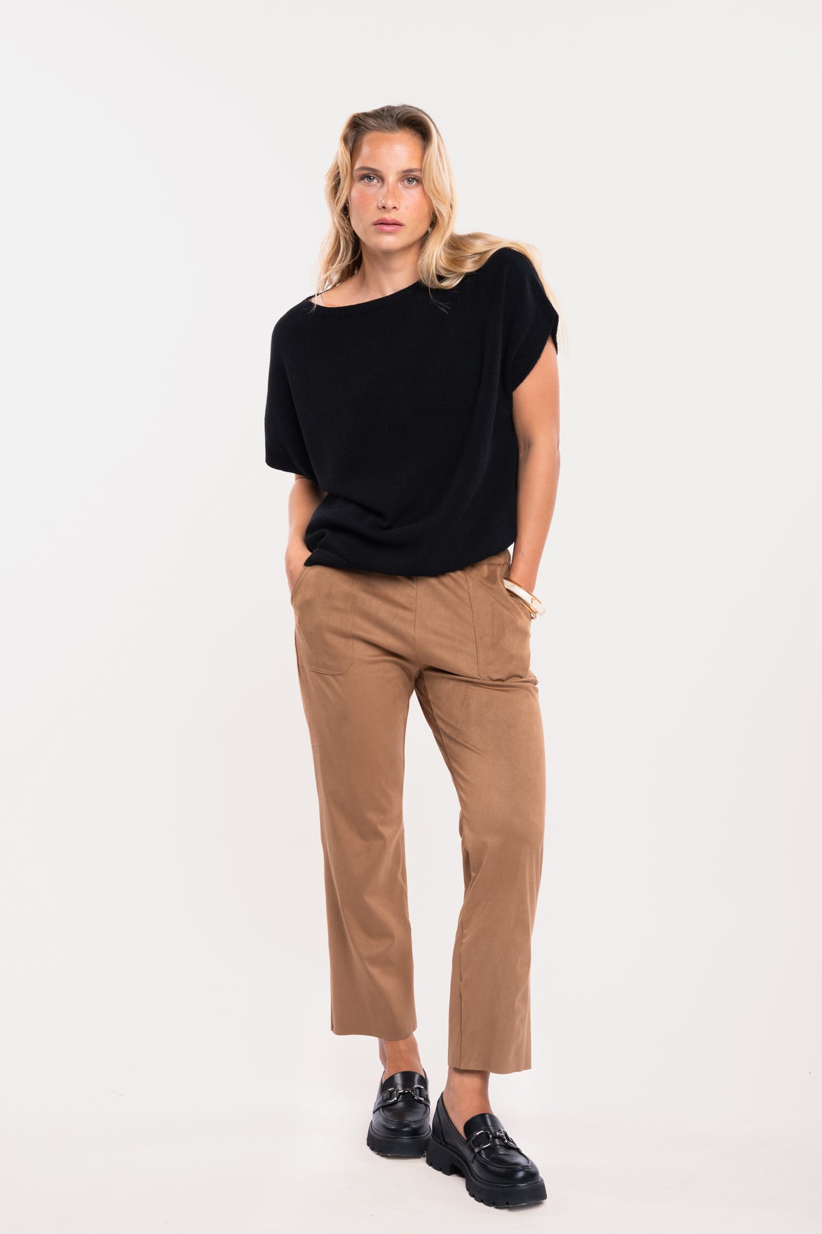 Pull sans manches noir avec un pantalon suédine cintré camel avec une paire de mocassins noirs