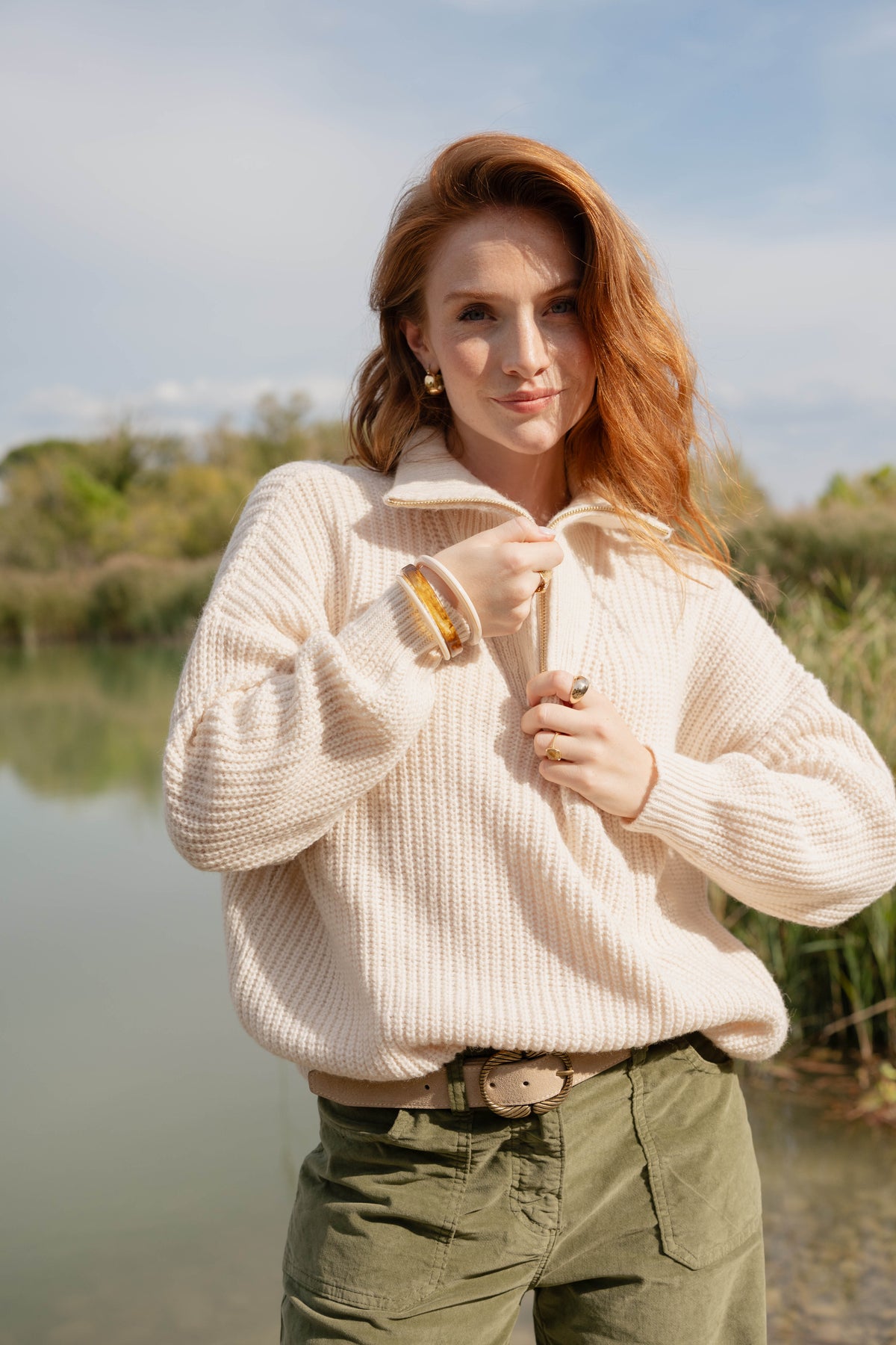 Pull écru, pantalon long en velours kaki, et ceinture écru