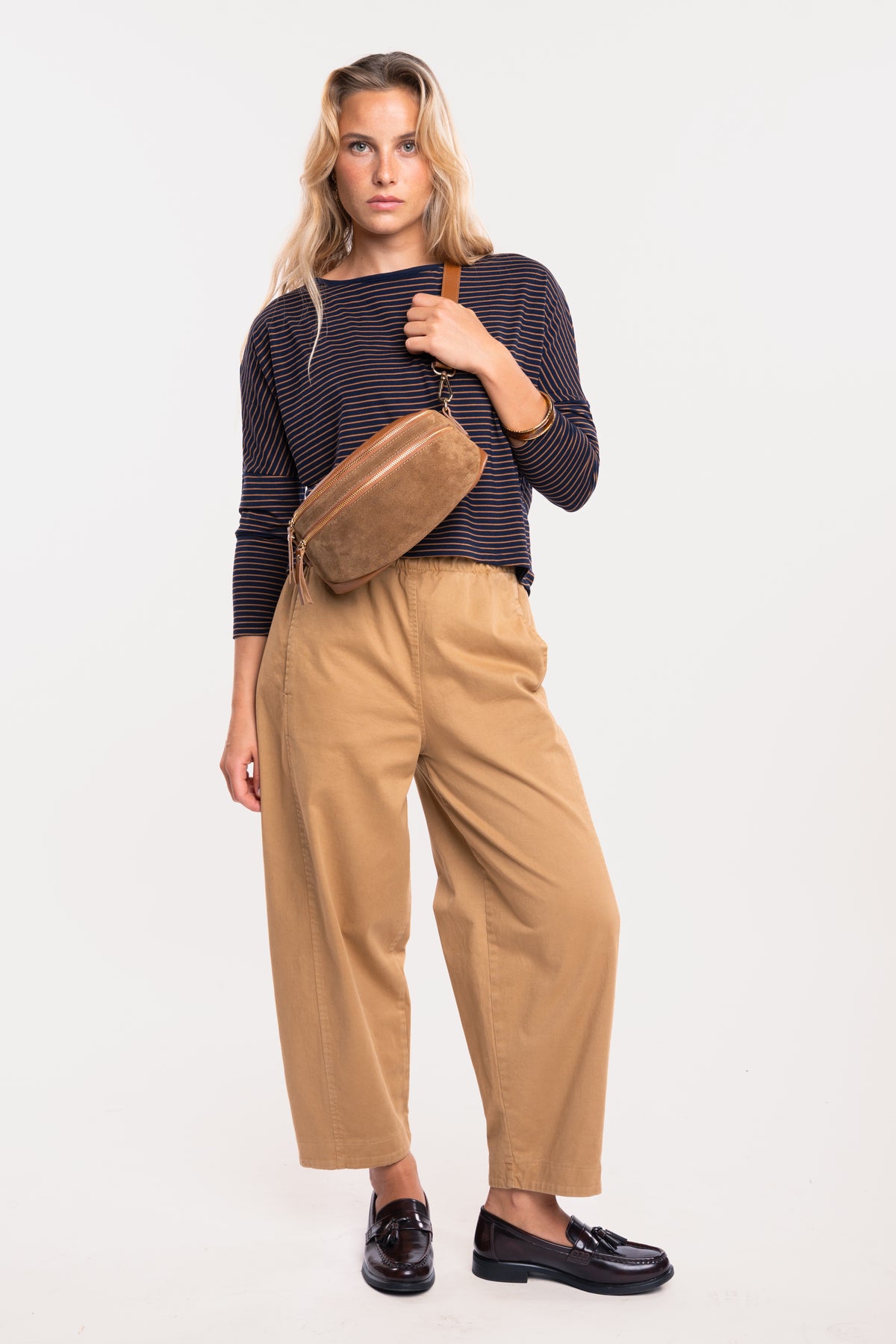 Sac banane en cuir camel, top col bateau rayé marine et camel avec un pantalon barrel camel et une paire de mocassins 