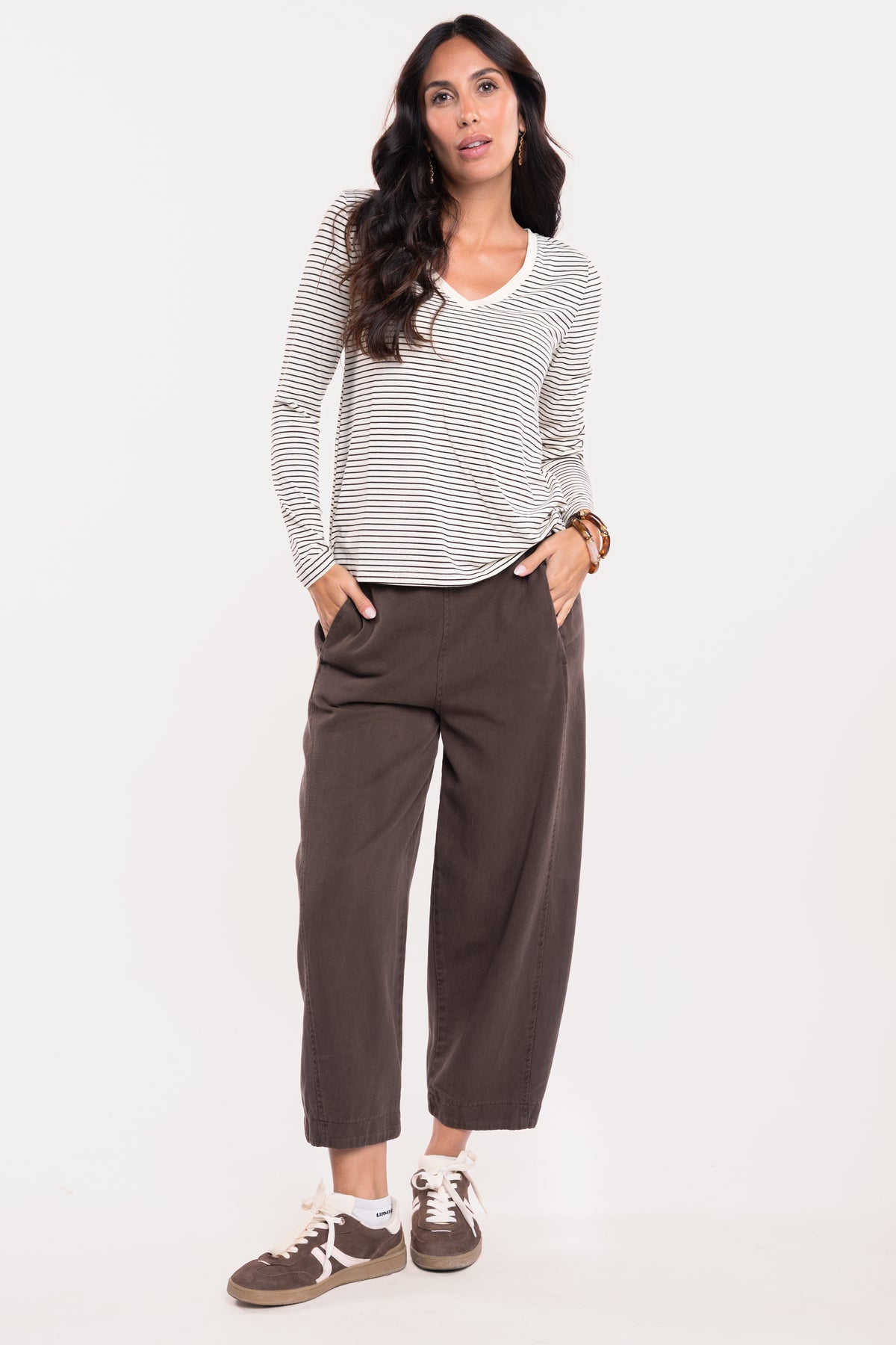 Un T-shirt rayé écru et marron, un pantalon barrel marron et une paire de baskets marron