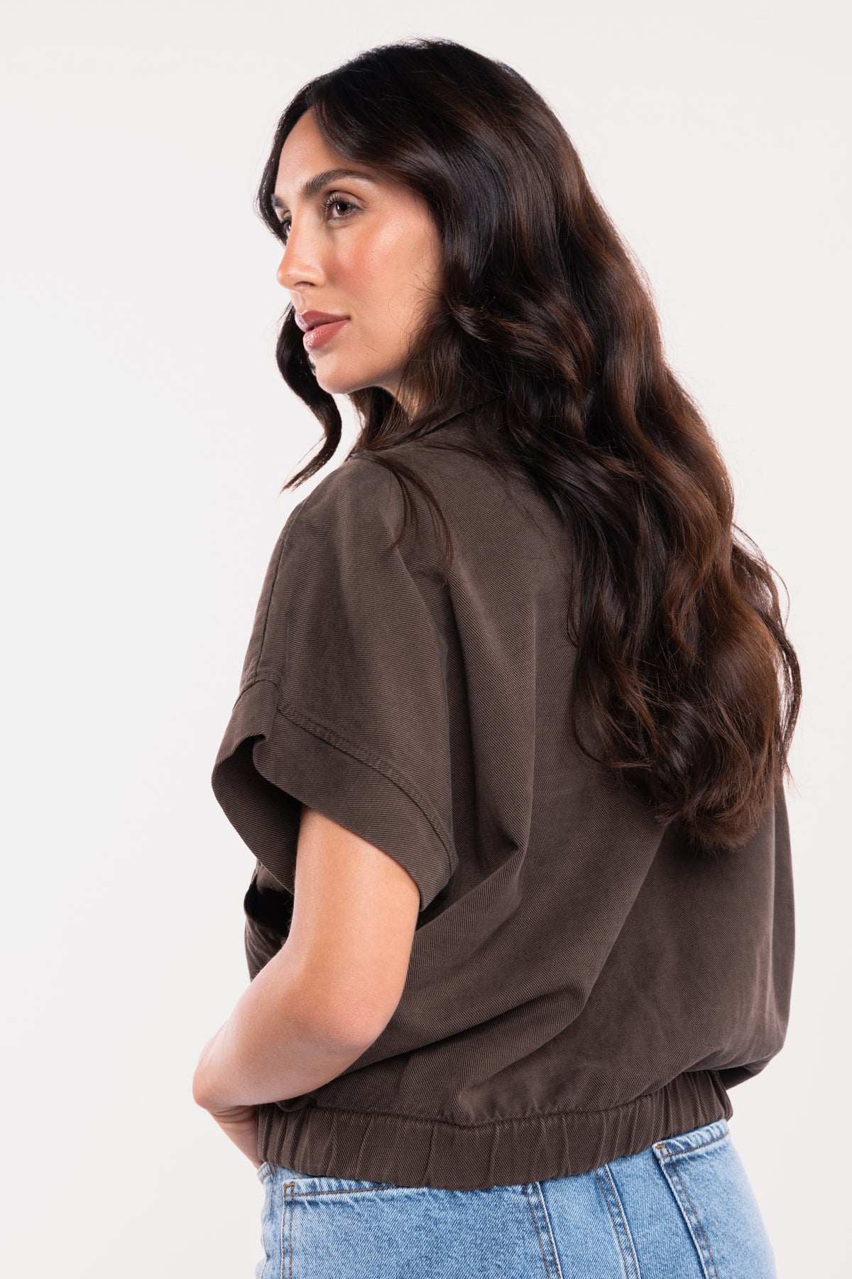Une veste sans manches marron et un jean évasé délavé clair