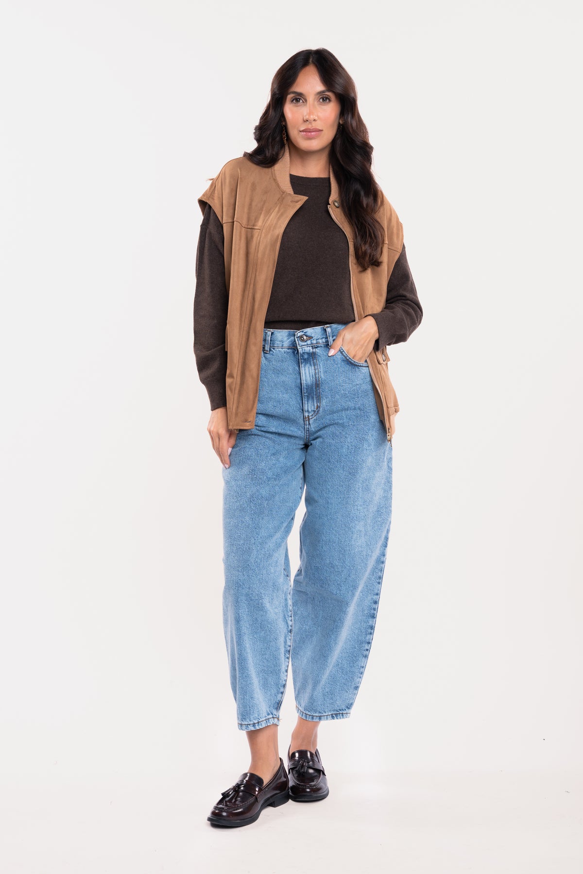 Veste sans manches suédine camel avec un pull oversize marron, un jean barrel délavé clair et une paire de mocassin 