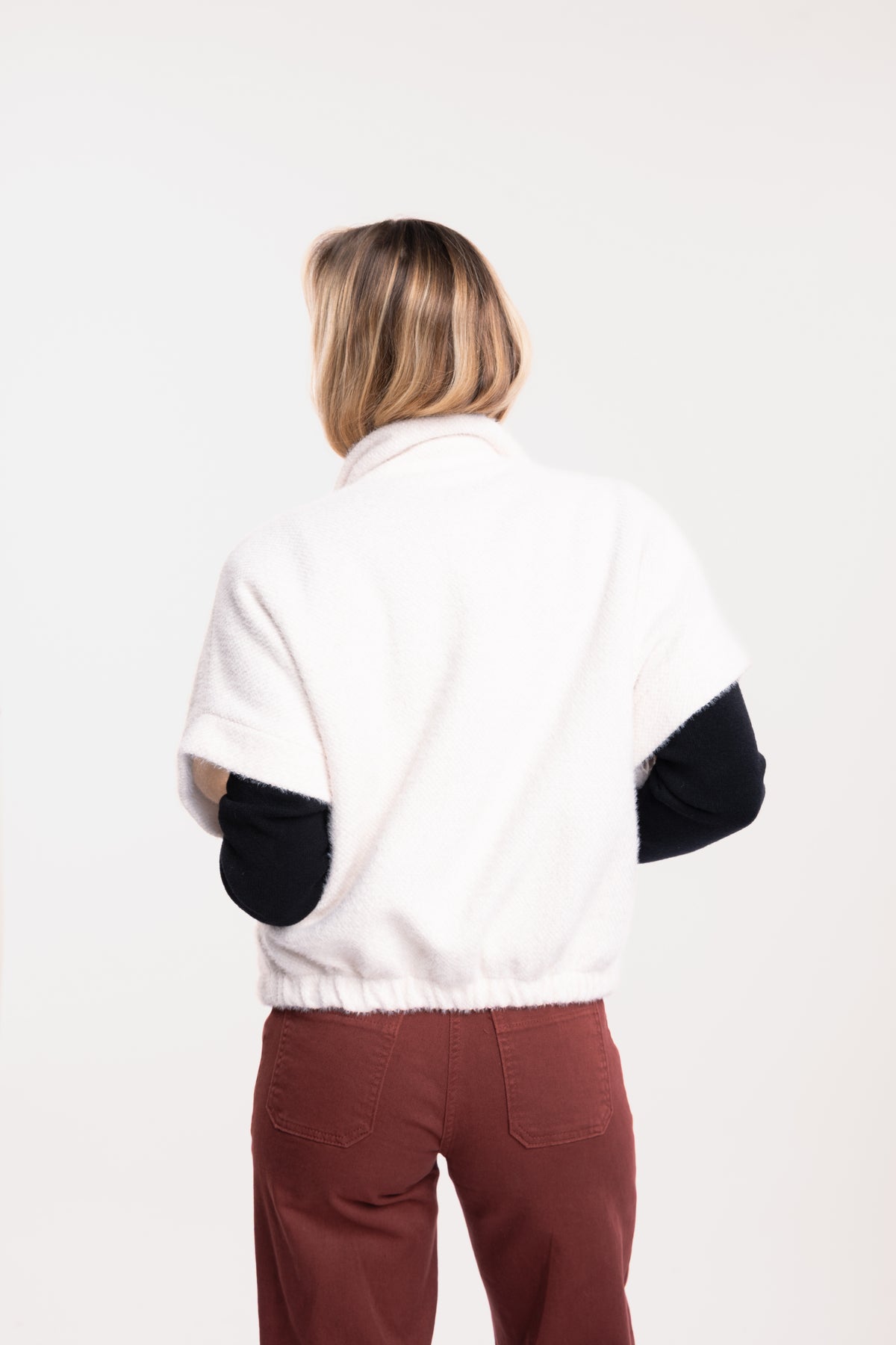 Veste zippée écru avec pull ample col v noir et pantalon 7/8ème acajou de dos