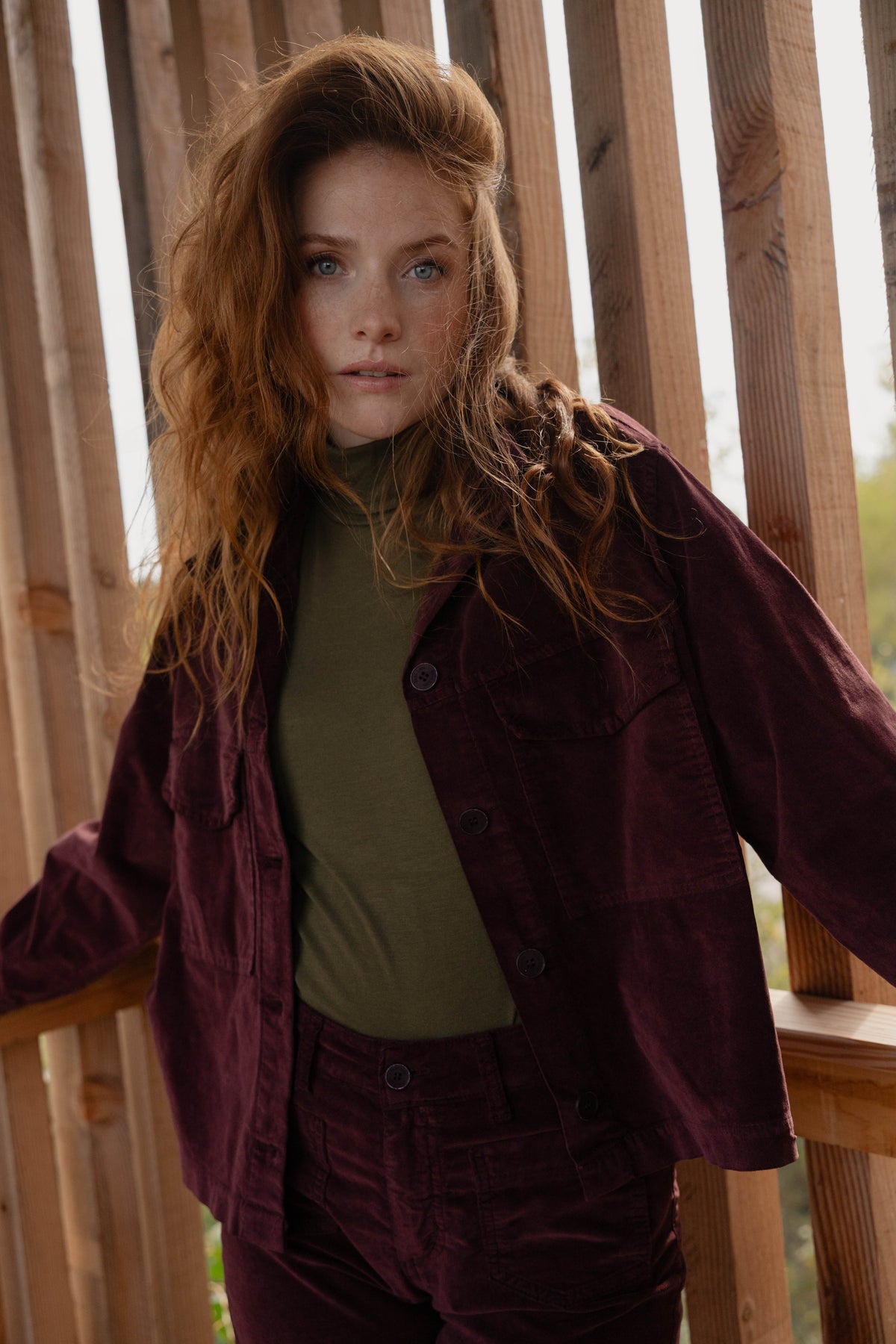 Veste en velours bordeaux avec un teeshirt col roulé kaki, un pantalon long en velours